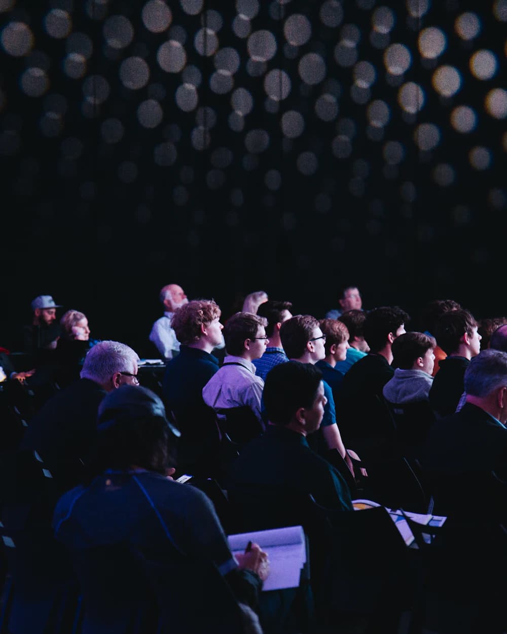 Une salle pleine, le public tourné vers la scène pendant une conférence.
