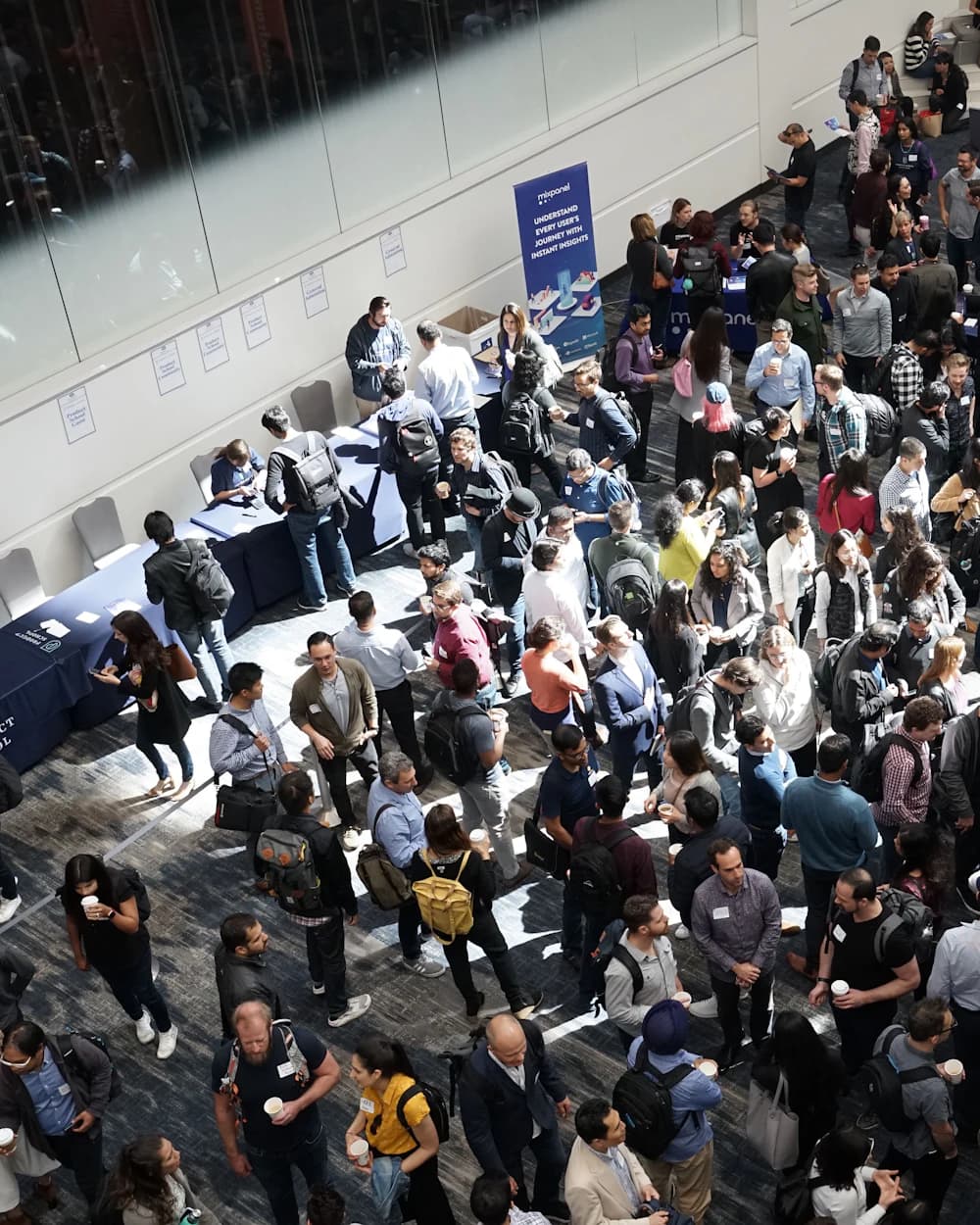 Une foule dense circule entre les stands d'un salon professionnel, vue de haut.